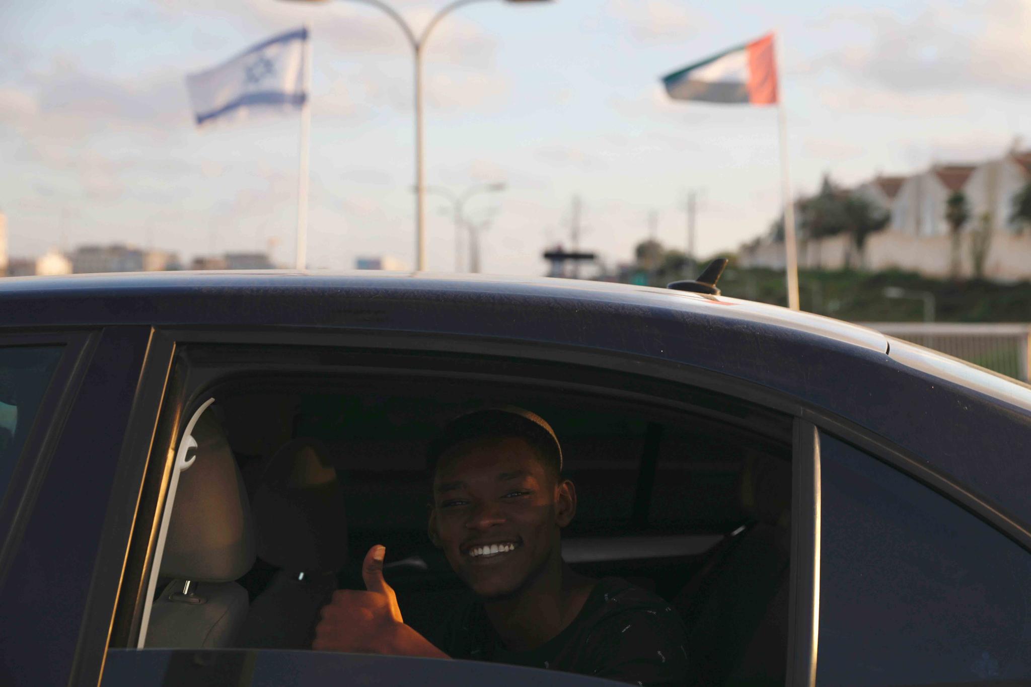 A man gives a thumbs up as he passes United Arab Emirates and Israeli flags at the Peace Bridge in Netanya, Israel, Sunday, Aug. 16, 2020.