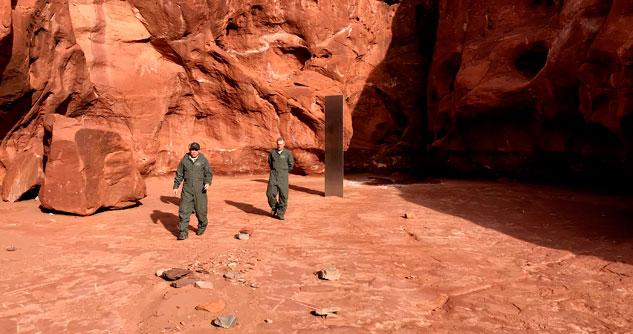 Utah state workers walk near a metal monolith