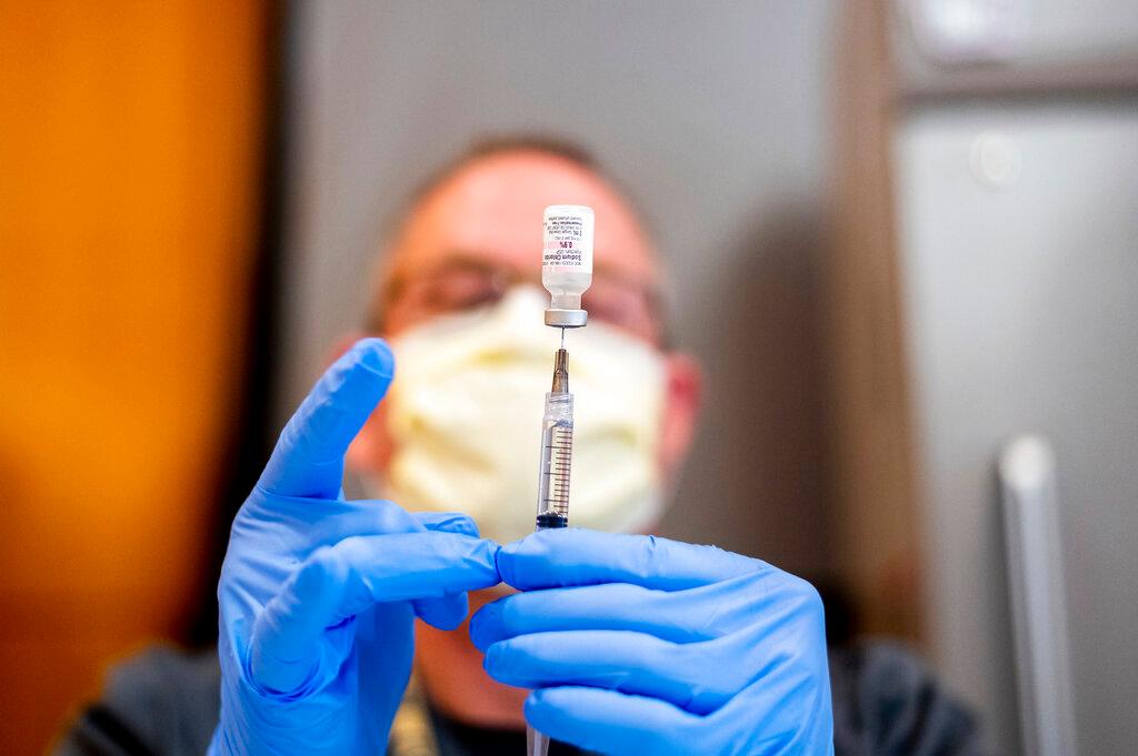 Pharmacist Brian Kiefer draws saline while preparing a dose of Pfizer's COVID-19 vaccine at UC Davis Health