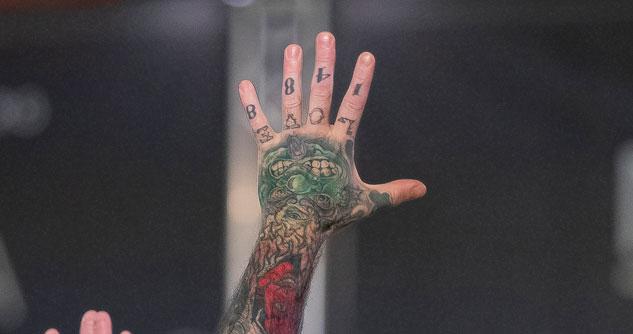 Man's tattooed hand reaching skyward