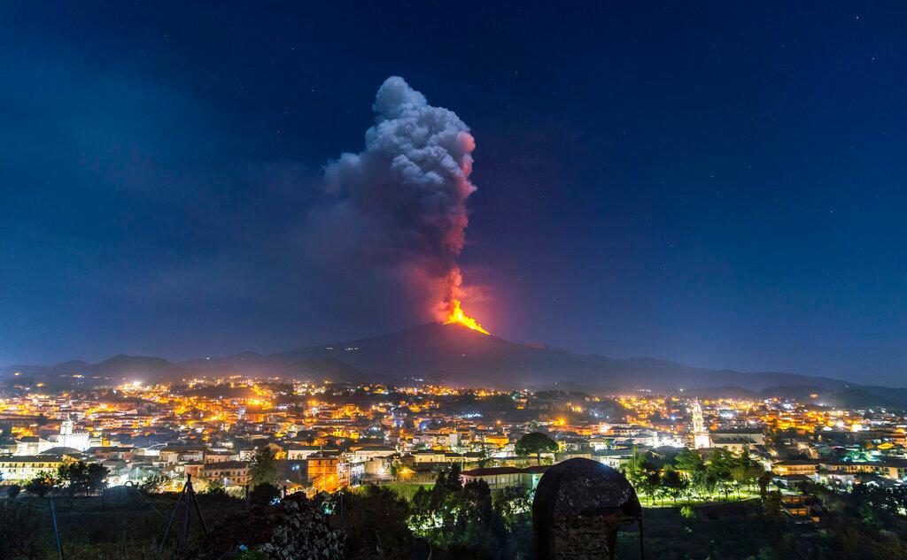 Flames and smoke billowing from a crater, as seen from the southern side of the Mt Etna volcano, tower over the city of Pedara, Sicily
