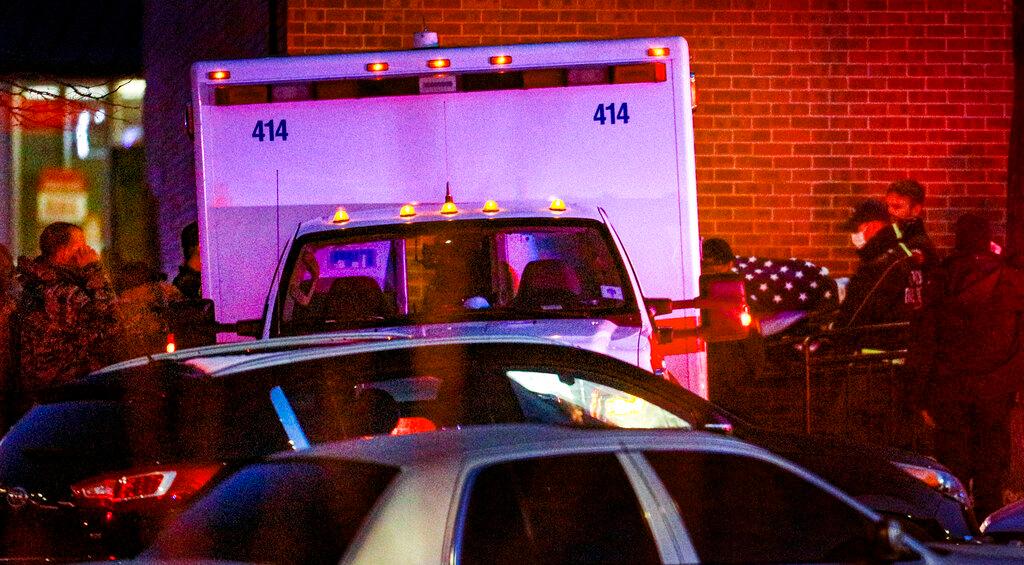 A flag-covered gurney is wheeled to an ambulance outside a King Soopers grocery store