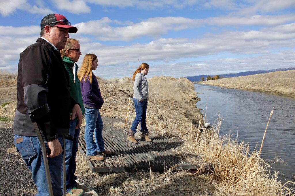 armer Ben DuVal, his wife, Erika, and their daughters, Hannah, 12, in purple, and Helena, 10, in gray, stand near a canal for collecting run-off water near their property in Tulelake, Calif. 