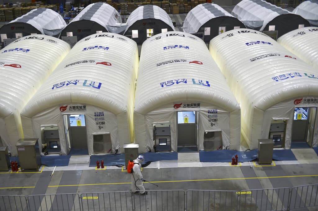 A worker disinfects the flooring outside the inflated cabins at the pop-up Huo-Yan Laboratory set up in an expo center to test samples for covid-19 virus in Nanjing in east China's Jiangsu province