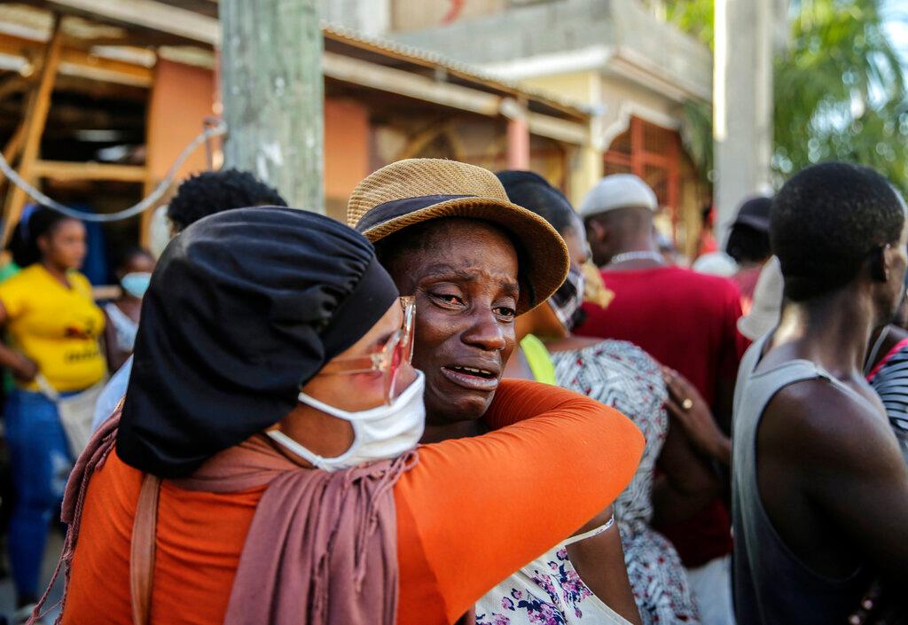People cry during the search for those who are still missing in a house destroyed by the earthquake in Les Cayes, Haiti