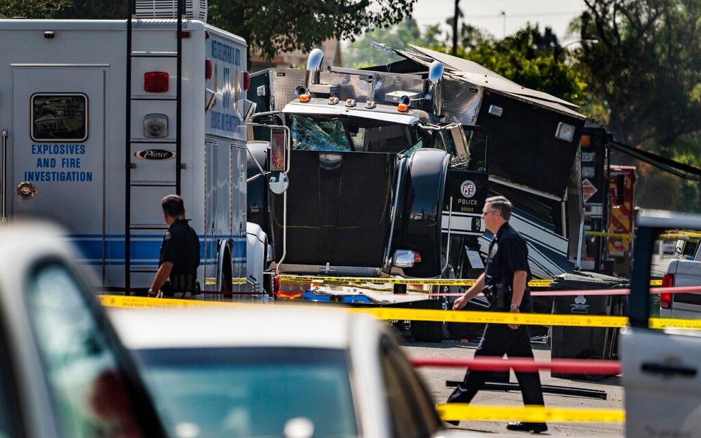 Police walk past the remains of an armored tractor trailer 