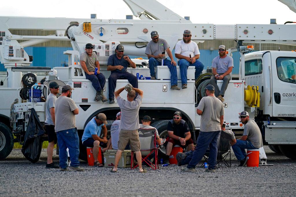 Electrical workers congregate in the evening after parking their trucks after a day's work at a tent city in Amelia, La.