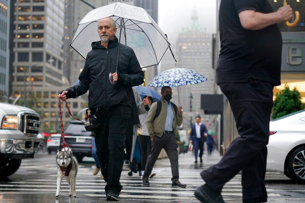 Pedestrians make their way through a rainy and foggy New York