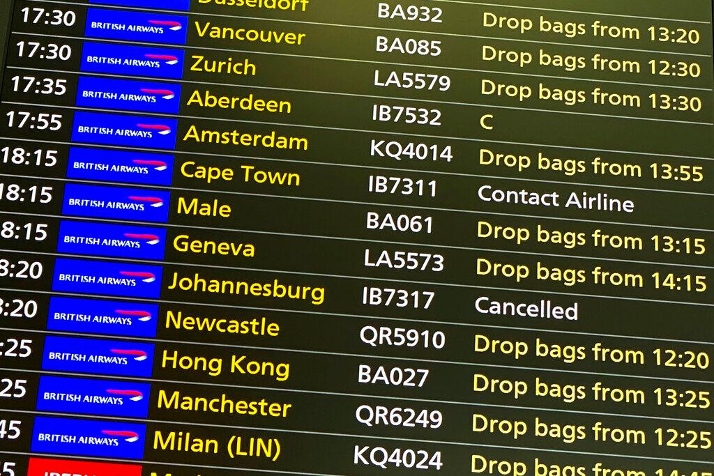 A departures screen displays a cancelled flight to Johannesburg and a message to contact the airline for a scheduled flight to Capetown, at London's Heathrow Airport