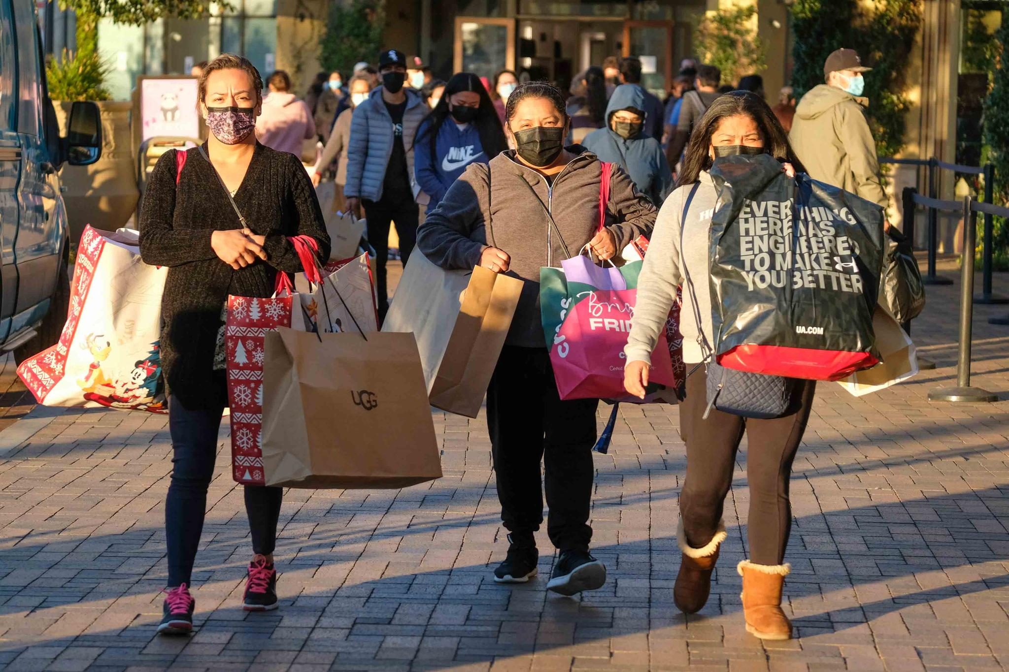 Black Friday shoppers wearing face masks carry bags at the Citadel Outlets in Commerce, Calif., Friday, Nov. 26, 2021.