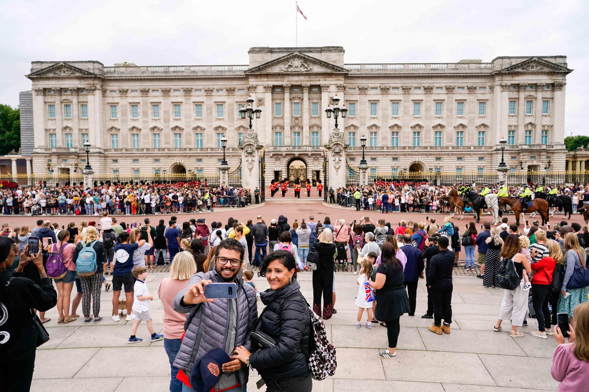 Members of the public watch the Changing of the Guard ceremony at Buckingham Palace, London, Aug. 23, 2021, which is taking place for the first time since the start of the coronavirus pandemic.