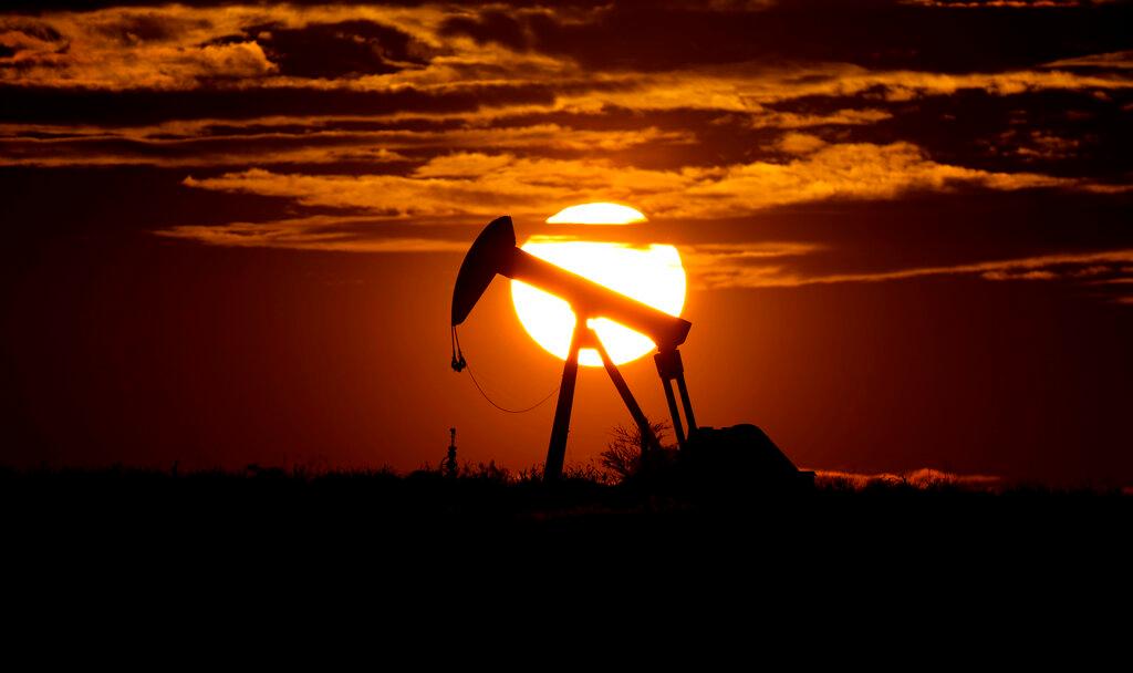 The sun sets behind an idle oil pump jack