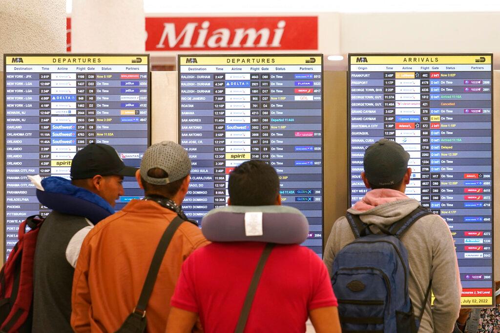 Travelers check their flights at Miami International Airport, Saturday, July 2, 2022, in Miami. The Fourth of July holiday weekend is jamming U.S. airports with the biggest crowds since the pandemic began in 2020.