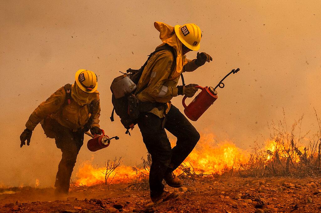 Firefighters burn vegetation while trying to keep the Electra Fire from reaching homes in the Pine Acres community of Amador County, Calif.
