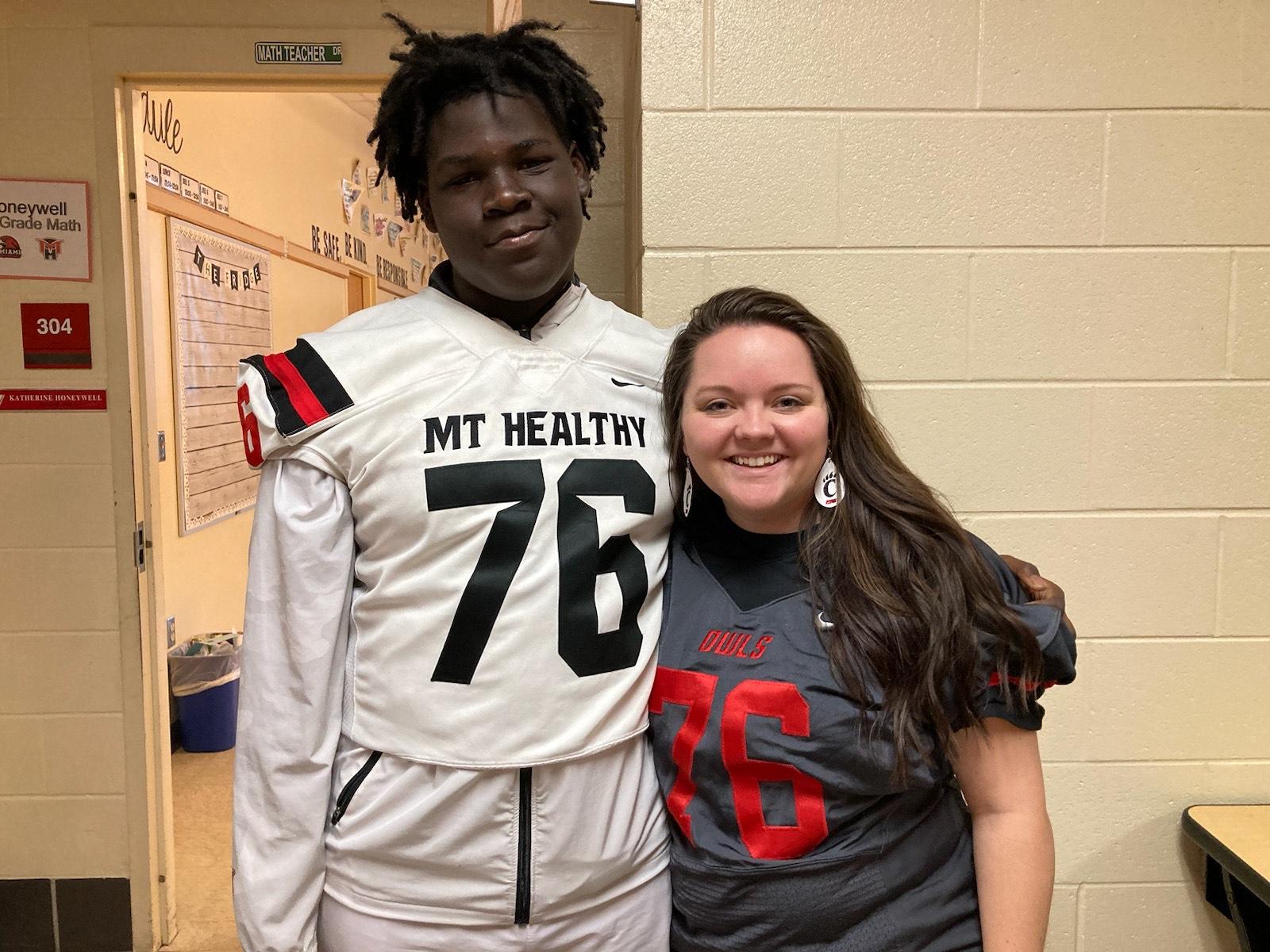 Mt Healthy High School staff member and student posing with football jerseys