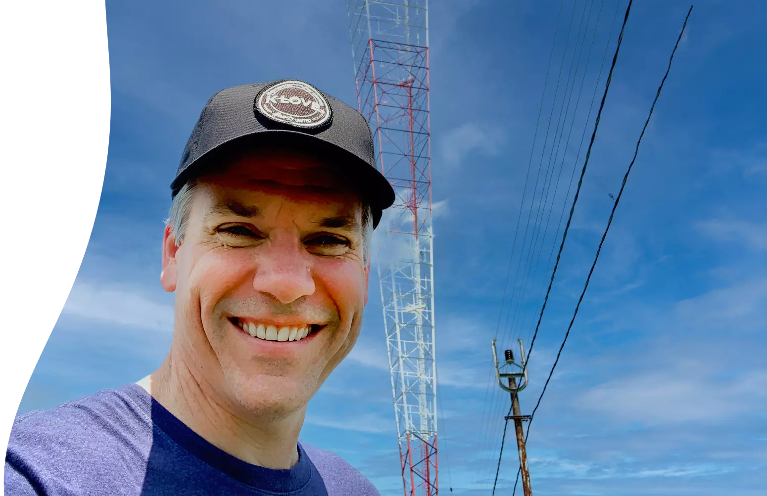 happy engineer smiling in front of a k love radio tower